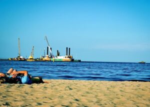 Der Strand von Swinemünde mit der Mole, die als Warenumschlagplatz dient, in unmittelbarer Nähe zum Strand.